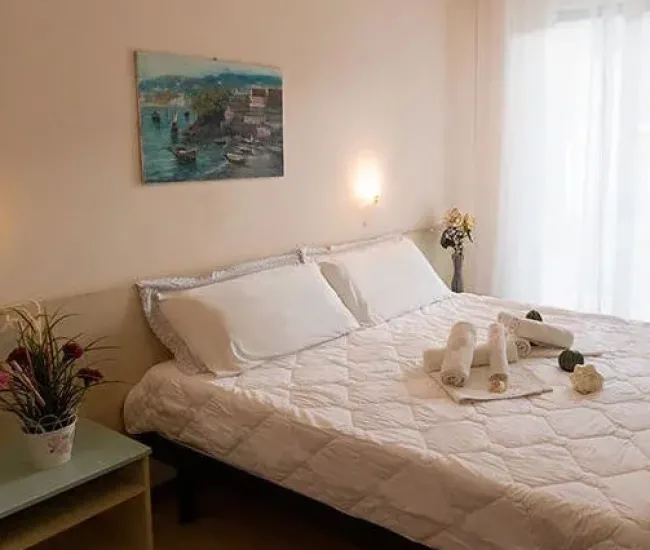 Camera da letto luminosa con letto matrimoniale e decorazioni semplici.